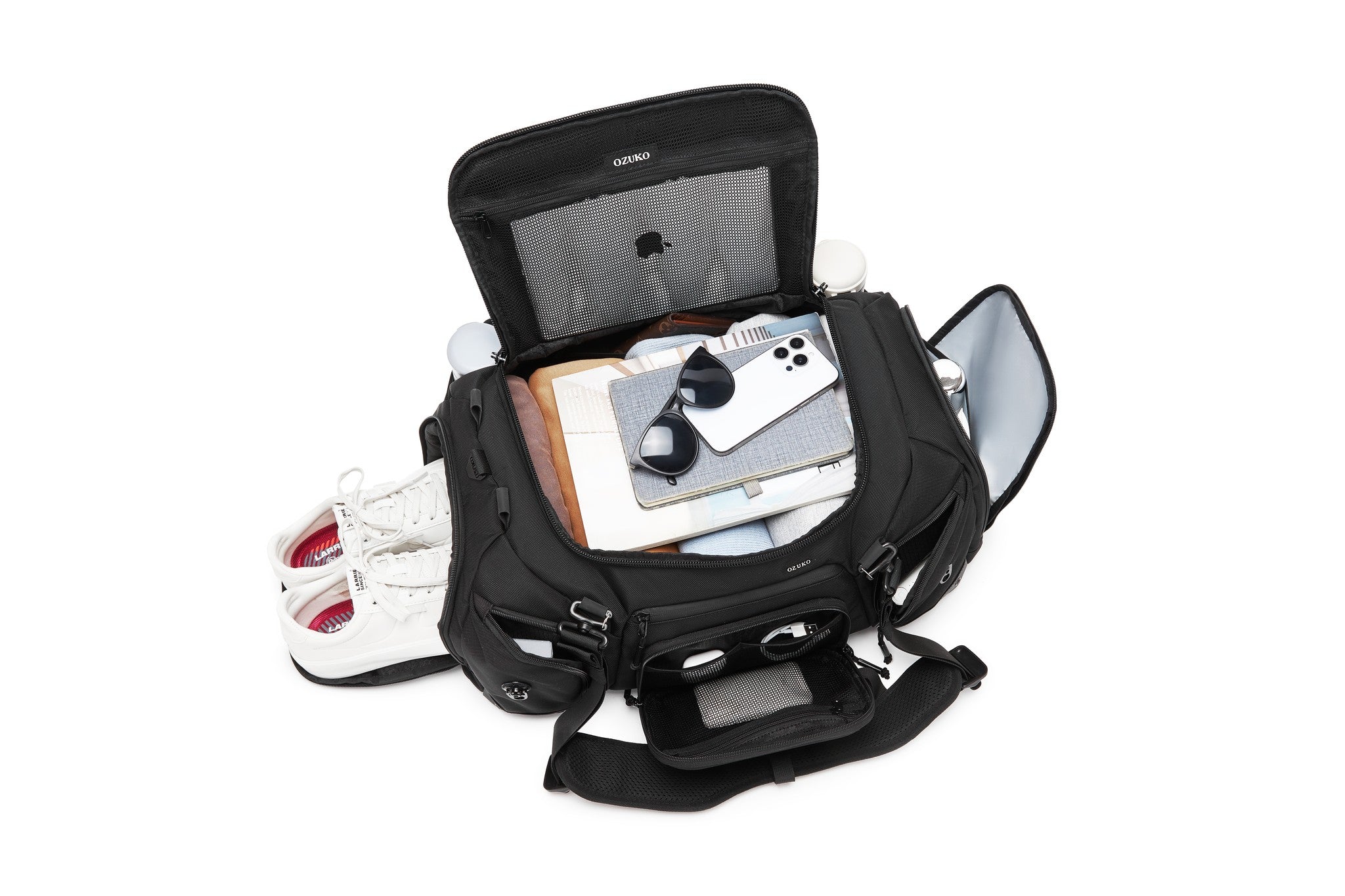 Black Voyager Duffel 40L interior lid pocket packed with white sneakers, a notebook, sunglasses, and a phone